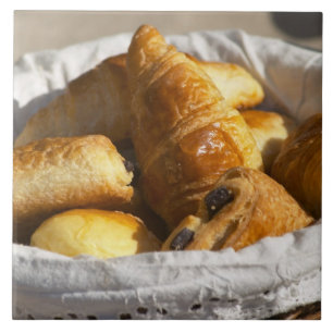 En flätad frukostkorg med croissanter, och kakelplatta