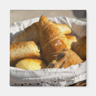 En flätad frukostkorg med croissanter, och magnet