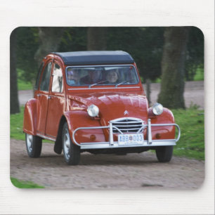 En gammal röd Citroen 2CV bil med en leende kvinna Musmatta