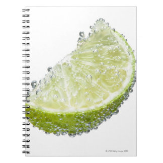 En juicy mogen ekologisk limekilfrukt nedsänkt anteckningsbok med spiral