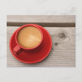 En ljusröd kopp av espressokaffe på en picknick vykort