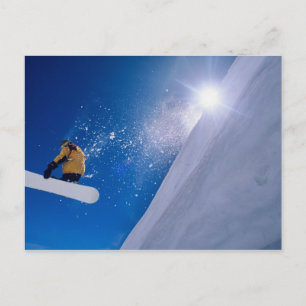 En man som flyger genom luft på en snowboard med vykort