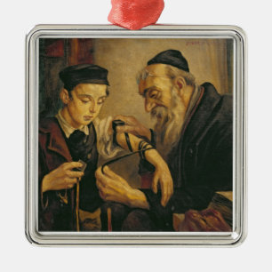 En rabbin som binder phylacteriesna till armen av julgransprydnad metall