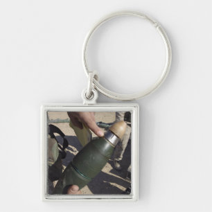 En squadledare pekar till en fyrkantig silverfärgad nyckelring