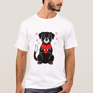 En svart valp som håller ett rött hjärta t shirt