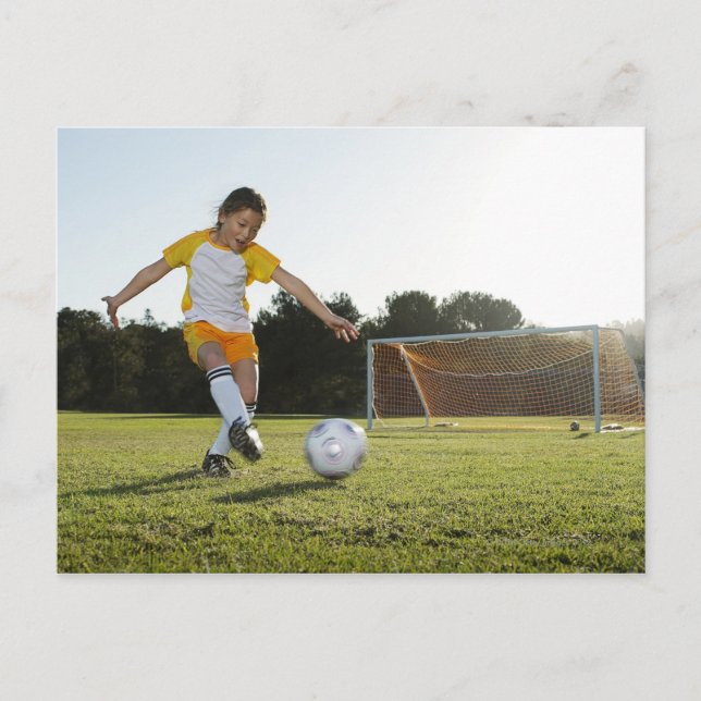 En ung flicka som spelar fotboll på en fotboll fäl vykort (Framsida)