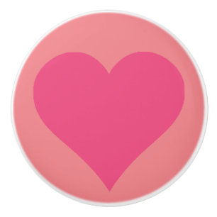Enkel rosa hjärtkeramikdragknapp på rosa bakgrund knopp