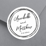Enkelt minimalistiskt Namn Red Hand plockade Bröll Runt Klistermärke<br><div class="desc">Små, minimalistiska bröllopstångar med svart Doodle Ram. De här charmerande fyrkantiga vigselklistermärkena har briden och brudgummens datum namn och bröllop som visas i en blandning av ren och snyggt typsnitt. Att omge designen är en lekfull, handdragen, svart doodle ram av ogenomskinliga cirklar, som tillför en roligt och en vismisk beröring....</div>