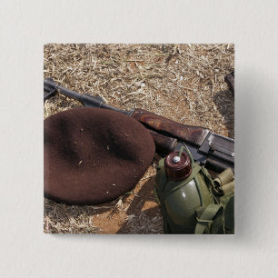 Ett gevär, militär täcker och kantinen knapp