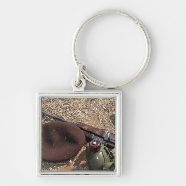 Ett gevär, militärt täcke och matsal fyrkantig silverfärgad nyckelring (Framsidan)