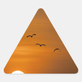 Fåglar som flyger i solnedgång triangelformat klistermärke