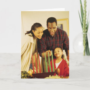 Familj som tänder Kinaraen för Kwanzaa Helgkort