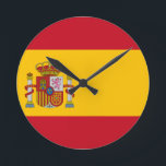 flagga rund klocka<br><div class="desc">Flagga Spanien (spanska: Bandera de España), enligt definitionen i den spanska konstitutionen från 1978, består av tre vågrät rand: Rött, gult och rött. gulten rand är dubbelt så storlek som varje rött rand. Traditionellt har mitten rand definierats genom gualdas mer arkaiska beteckning, och därmed det populära namn la Rojigualda (rödsvetsade)....</div>