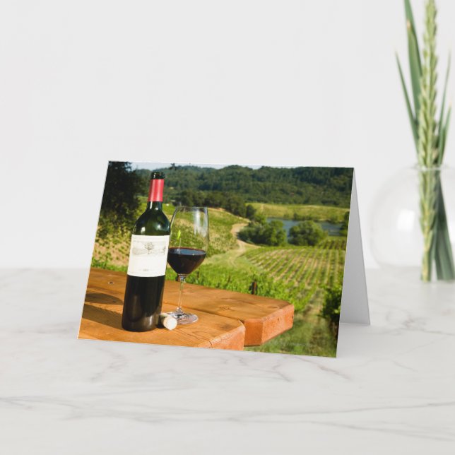 Flaska av rött vin och exponeringsglas på bord kort (Framsida)