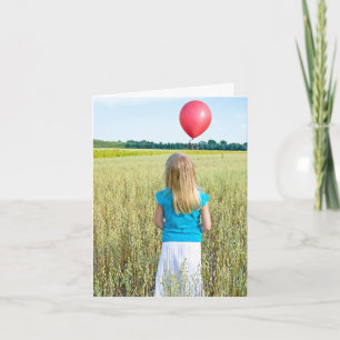 flicka i vete fält med röd ballong kort