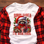 Förlåt att Santa jag har varit Feral Cute Raccoon  T Shirt<br><div class="desc">Den här konstiga och humoristiska julskjortan har en vacker tvättbjörn klädd i en julhatt och mysigt vinterscarf, med den lekande frasen "Förlåt att Santa I har varit Feral". Perfekt för dem som tycker om att lägga till lite vild helgdag till sin garderob, är denna design underbar för julfester eller bara...</div>