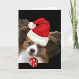 Förtjusande Papillon hund i en Santa hatt Helgkort