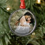 Foto Första julen med Elegant Vitskript Julgransprydnad Metall<br><div class="desc">Vi presenterar vår första "Engaged"-Anpassningsbar Photo Namn Ceramic Ornament, en verkligt speciell keepy för det nyligen engagerade paret. Med den här personligen kan du hedra minnet av denna glädjande milstolpe och lägga till en personlig beröring till Julgran. Utsmyckningen har ett skript för elegant som lyder "förlovad" och symboliserar detta spännande...</div>