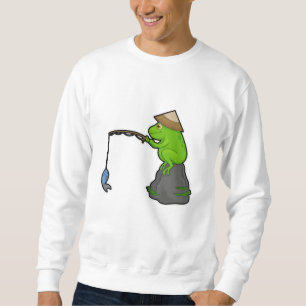Frog på sten vid fiske med fiskstav och fisk lång ärmad tröja