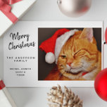 Funny God jul Orange Cat med Santa Hat<br><div class="desc">Det här fina julkortet kommer säkert att sprida glädje till kattälskare och alla däremellan! Framsidan har en oemotståndligt söt orange tabby katt, som på ett snyggt sätt vinkar medan den bär en feg röd julhatt. Vid sidan av det här charmerande kattdjuret står det: "God jul från ANDERSSON FAMILY", med ett...</div>