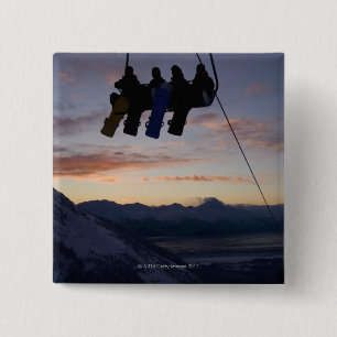 Fyra snowboarders silhouetteds på en skidlift knapp