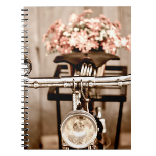 Gammal cykel och blommor oskärpa i bakgrunden proc anteckningsbok