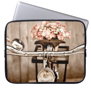Gammal cykel och blommor oskärpa i bakgrunden proc laptop fodral