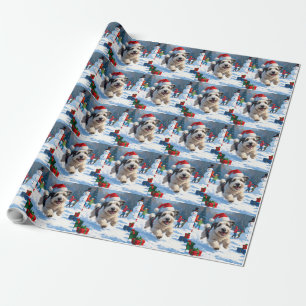 Gammal engelsk herdehund springer i snö julhatt presentpapper