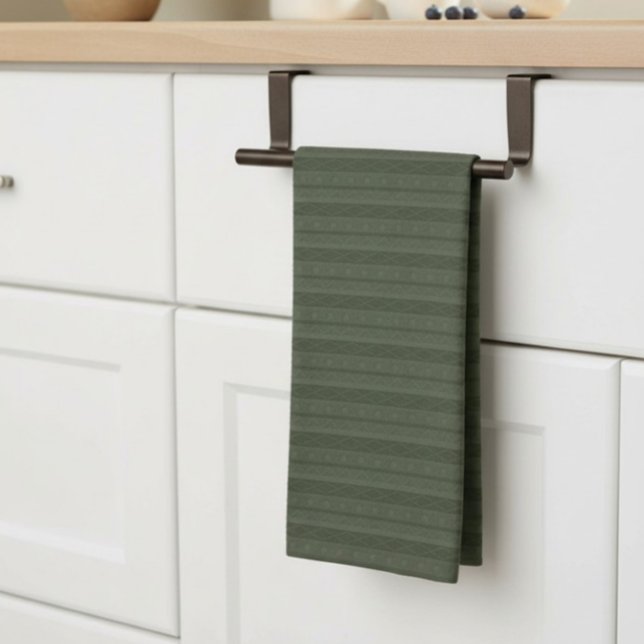 Geometrisk Aztec Olivgrön Randig Kökshandduk (geometric, striped, deep green tea towel, neatly hung on a bar on a kitchen counter.)