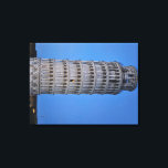 Gift Bag Canvastryck<br><div class="desc">This captivating photograph showcases the iconic Leaning Tower of Pisa standing elegantly against a deep blue twilight sky in Pisa. The historic marble tower, famous for its unmistakable tilt, is beautifully illuminated, highlighting its intricate Romanesque arches and layered columns. The soft evening light creates a striking contrast between the glowing...</div>