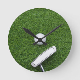 Golf boll med putter är på grönt gräs rund klocka