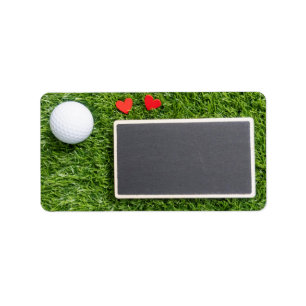 Golf boll med två hjärtan är på grönt med br adressetikett