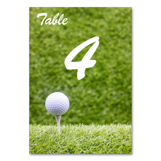 Golfbollar på tee på grön gräsmatta bordsnummer (Framsidan)