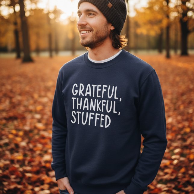 Grateful Thankful Stuffed • Funny Thanksgiving Lång Ärmad Tröja (Man wearing navy sweater with text “Grateful, Thankful, Stuffed” in autumn park)