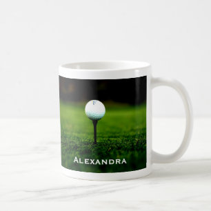 Grön grästorva och golfboll/utslagsplats, kaffemugg