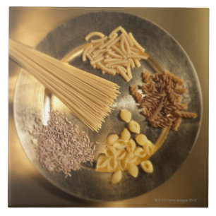 Guld pläterar med pasta och korn av vete kakelplatta