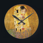 Gustav Klimt the Kiss Rund Klocka<br><div class="desc">Gustav Klimt Kiss Gustav Klimt använde guld i sitt vackra arbete med kvinnor och dekorativa konst i art nouveau. Klimtmålningen kallades "The Kiss" och är det mest välkända art nouveau han någonsin målat upp. Gustav Klimt-målningen är av en kvinna och man i art nouveau i ett omfamnande. Färg är överväldigande...</div>