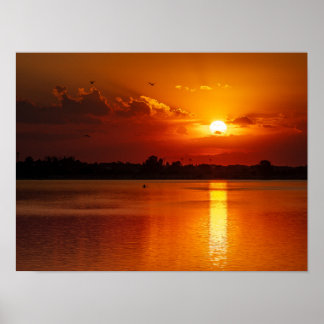 Gyllene apelsolnedgång över en lugn sjö poster