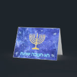 Hanukkah Snowstorm Menorah Helgkort<br><div class="desc">En glödande menorah guld Hanukkah och "Chag Chanukkah Sameach" (Lycklig Hanukkah) i glödande blå och vit text som läggs ovanpå en blå och vit fraktalbild som påminner om snöflingor i en storm.</div>