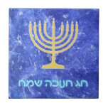 Hanukkah Snowstorm Menorah Kakelplatta<br><div class="desc">En glödande menorah guld Hanukkah och "Chag Chanukkah Sameach" (Lycklig Hanukkah) i glödande blå och vit text som läggs ovanpå en blå och vit fraktalbild som påminner om snöflingor i en storm.</div>