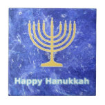 Hanukkah Snowstorm Menorah Kakelplatta<br><div class="desc">En glödande guld Hanukkah-menorah och "Lycklig Hanukkah" i blått och vitt text som läggs ovanpå ett blått och vitt skenbart mönster som påminner om snöflingor i en storm. Chag Sameach!</div>