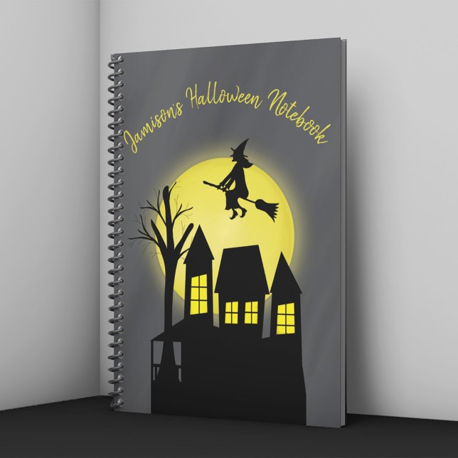 Hemma hus och flygande väst med månljus anteckningsbok (Spooky Halloween notebook with witch flying over haunted house and glowing full moon.)