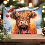 Highland Cow Santa Hat Cute jul Helgkort<br><div class="desc">Fira julhelgen med detta vackra julkort med en charmerande högreko som bär en julhatt. I festscenen finns snö-täckt träd och ett glatt "Glad helg" hälsning i rött. Perfekt för att tillföra stollig och värme till dina semesterhälsningar, det här kortet ger säkert ett leende till någons ansikte. Idealisk för djur älskare...</div>