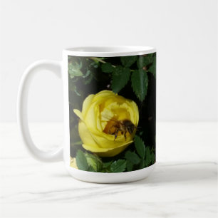 Honungbi som pollinerar gul ros kaffemugg