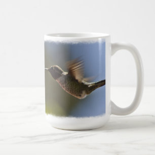Hummingbird vid flygning mot vitt kaffemugg