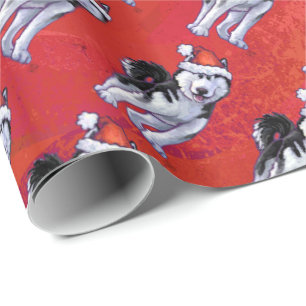 Husky i den Santa hatten på rött Presentpapper