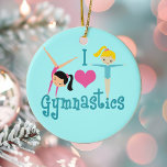 I Kärlek Gymnastics Julgransprydnad Keramik<br><div class="desc">I Kärlek Gymnastics. En söt gymnastik-flickpresent med ätliga tealtext mellan två söta,  tumlande små flickor och ett vackert rosa hjärta. En söt gymnast närvarande för ett barn eller för kvinnors gymnastiktränare. En brunett i ett handställ och en blond flicka med förlängd arm.</div>