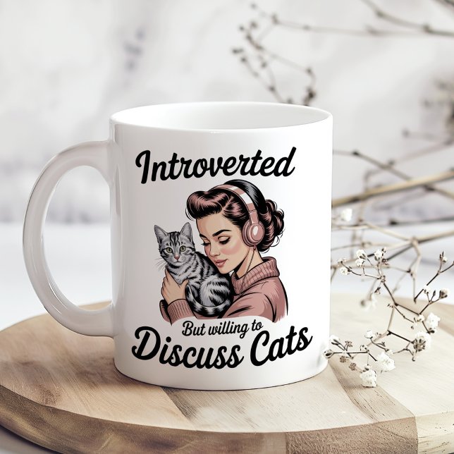 "Introverted But Willing to Discuss Cats" Funny Kaffemugg ("Introverted But Willing to Discuss Cats" Funny Coffee Mug on a sunny boho kitchen table.)