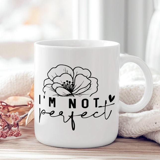 "Jag är inte Perfekt" Svartvit Blommigt Kaffemugg ("I'm Not Perfect" Black and White Floral Coffee Mug on a sunny boho wooden table with pink flower.)