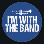 Jag är med Band Funny Trumpet Runt Klistermärke<br><div class="desc">En humor-design för coolans marchband för en bandgäst som spelar upp trumpet som läser att jag är Med bandet i ett grunge-teckensnitt. Lustigt blå trumpetergåva.</div>